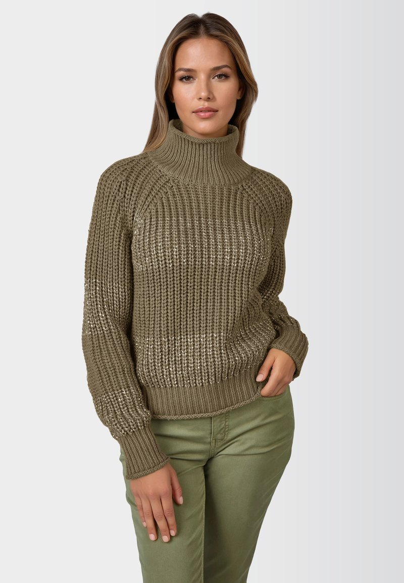 Olivgrüner gestrickter Pullover mit hohem Kragen, strukturiertem Muster und gerippten Bündchen; kombiniert mit olivgrünen Hosen.