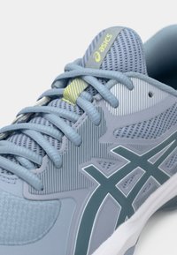 Αθλητικό παπούτσι ανοιχτού γαλάζιου χρώματος με επάνω μέρος από δίχτυ, υφασμάτινα πάνελ με υφή και αντιθετικές σκούρες μπλε λεπτομέρειες. Διαθέτει επίπεδα κορδόνια και λογότυπο στη γλώσσα.