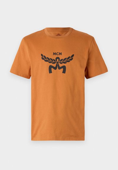 T-shirt de algodão laranja com mangas curtas, apresentando um design gráfico preto com folhas de louro e o texto "MCM" impresso na parte frontal.
