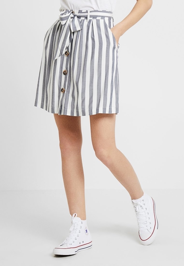 Randig kjol i marinblått och vitt, med ett knytbälte, framknappar, sidofickor och en utflädd nederkant. Matchas med vita högstövlar.