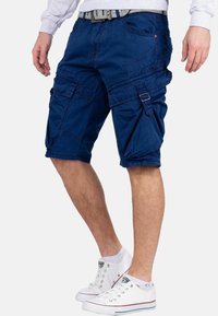 Shorts cargo bleu marine avec plusieurs poches, boucles réglables et ourlets roulés. Fabriqués en tissu léger, présentant une coupe décontractée.