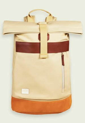 Mochila beige con cierre enrollable, correa y parche de cuero marrón, base de ante naranja, bolsillo frontal con cremallera vertical y asa superior para llevar.