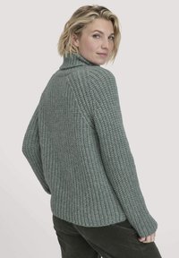 Dicker Strickpullover in gedämpftem Blaugrün, mit einem Stehkragen, gerippter Textur, überschnittenen Schultern und einer lockeren Passform mit seitlichen Schlitzen.