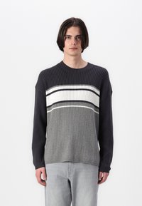 Gray ribbed knit sweater featuring a gradient design with white and dark gray stripes across the chest. Long sleeves and crew neckline.