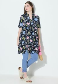 Blommig klänning i marinblått med korta ärmar och ett lager på lager-design; matchad med ljusblå leggings och beigea tofflor.