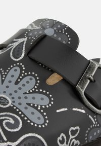 Infradito neri con motivi floreali grigi, cinturino con fibbia e dettagli a intaglio. Realizzati in materiale sintetico con finitura strutturata.