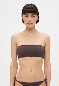 Brun bandeau bikini topp i glatt stoff, uten feste. Kombinert med matchende lav høyde bikini bunn med bindeside detaljer.