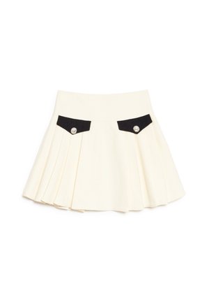 Jupe plissée crème avec rabats de poche avant noirs, chacun fixé par un seul bouton décoratif argenté.