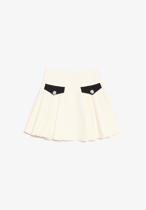 Cremefarbener Faltenrock mit schwarzen vorderen Taschenklappen, die jeweils mit einem einzelnen dekorativen silbernen Knopf gesichert sind.