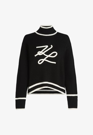 Schwarzer Strickpullover mit hohem Kragen, weißen Akzenten an den Manschetten und dem Saum, sowie einem auffälligen weißen Logo-Graphic auf der Vorderseite.