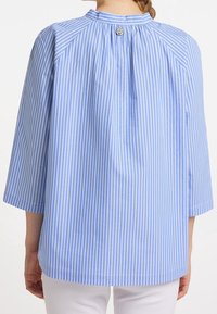 Blå- och vitrandig blus med rund halsringning, trekvartslånga ärmar och knappdetalj bak. Tillverkad av lättviktsmaterial.