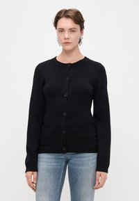 Μαύρο μακρυμάνικο κασκόλ από μαλακό υλικό, με στρογγυλή λαιμόκοψη, κλείσιμο με κουμπιά και δύο μπροστινές τσέπες με ριμπ λεπτομέρειες.