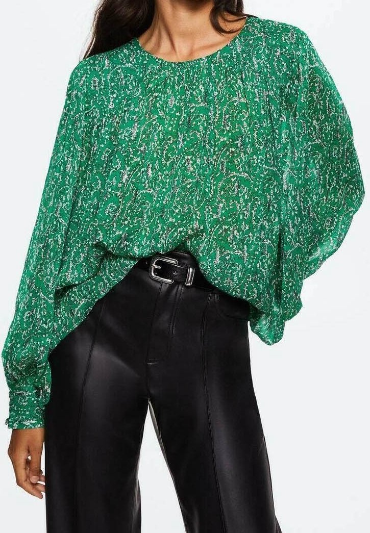 Blouse verte à motifs, coupe ample, manches longues et encolure ronde, associée à un pantalon noir en similicuir taille haute.