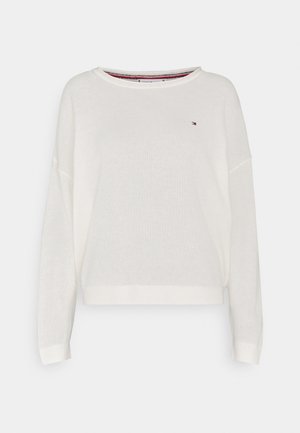 Biały dziergany sweter z szerokim dekoltem, opuszczanymi ramionami oraz ściągaczami na mankietach i dole. Na piersi znajduje się małe logo.