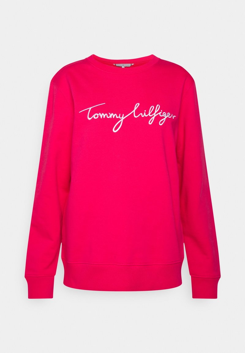 Sweatshirt à manches longues rose vif avec logo "Tommy Hilfiger" en écriture cursive blanche centré sur le devant.