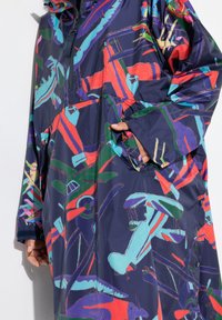 Impermeabile navy oversize con design astratti multicolore, dotato di zip, tasche e cappuccio. Realizzato in materiale leggero e resistente all'acqua.