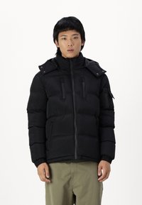 Schwarze Daunenjacke mit hohem Kragen, Reißverschluss vorne, zwei Brusttaschen und elastischen Bündchen, mit einer eleganten, gesteppten Textur.