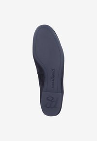 Suela de zapato plano de ante negro, con una parte inferior de goma suave, logotipo de la marca en relieve y tacón ancho. Diseño minimalista con líneas limpias.