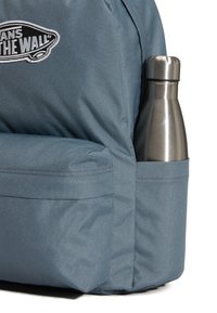 Niebieski plecak z materiału z boczną kieszenią na metalową butelkę na wodę. Materiał o fakturze oraz logo w czerni i bieli z przodu.