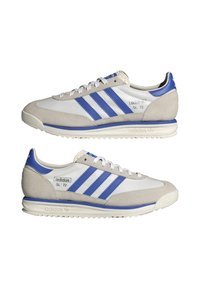 Zapatillas Adidas SL '72 blancas y grises con rayas y detalles azules, mostradas lado a lado mostrando los lados interior y exterior.