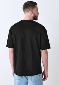 Black short-sleeve T-shirt made of cotton, featuring a relaxed fit and a round neck, with a smooth texture and no visible logos.