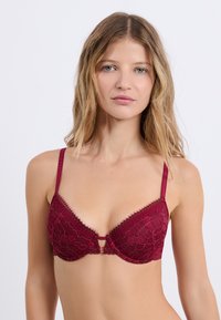 Burgunder Spitzen-BH mit Unterstüztung durch Bügel, verstellbaren Trägern, einem Schlüssellochdetail in der Mitte und floralen Mustern.