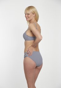 Pruhovaný bikinový set v námořnické a bílé barvě, s nastavitelnými popruhy a klasickým střihem. Tkanina má hladkou texturu a přiléhavý design.