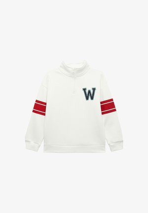 Valkoinen fleece-pullove, jossa on puolivetoketju, ja jolle on ommeltu tummansininen "W"-patch, sekä punaiset raidat hihoissa. Pehmeä materiaali ja rento istuvuus.