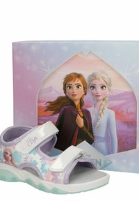 Παιδικό μωβ και λευκό σανδάλι θέμα Frozen με γραφικό της Έλσα και ρυθμιζόμενα λουριά, τοποθετημένο μπροστά από κουτί της ταινίας Frozen που δείχνει την Άννα και την Έλσα.