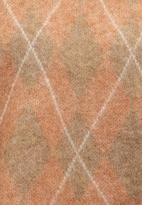 Pull en tricot avec un motif en losanges dans des teintes d'orange et de beige, avec des accents blancs, fabriqué en tissu en laine douce, présentant une surface texturée.