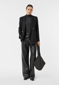 Czarny dwurzędowy blezer nałożony na prążkowany golf, zestawiony z wysokim stanem czarnych skórzanych spodni i teksturowaną pikowaną torebką.