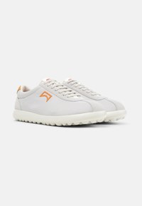 Hellgraue Sneakers aus Canvas mit strukturierter Oberfläche, versehen mit einem orangen Logo, weißen Schnürsenkeln und einer gepolsterten weißen Sohle.