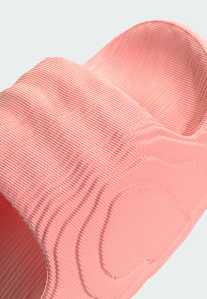 Sandale en caoutchouc rose avec des rainures texturées et un motif ondulé. Design à bout ouvert et bride profilée pour le confort et l'ajustement.