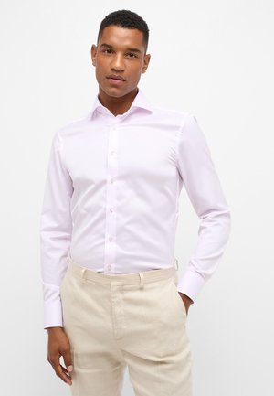 Lichtroze overhemd met lange mouwen van een gladde stof, met knoopsluiting aan de voorkant en een klassieke kraag, gecombineerd met beige broeken.