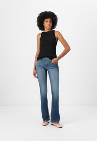 Black ribbed tank top, light blue flared jeans, and nude flats. The outfit features fitted shapes and a casual style with minimal accents.