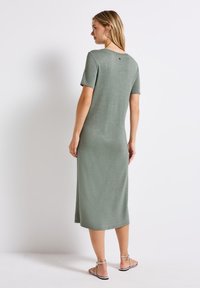 Sukienka do kolan, krótki rękaw, wykonana z miękkiego, metalicznego zielono-oliwkowego materiału, z okrągłym dekoltem i delikatnym połyskiem.