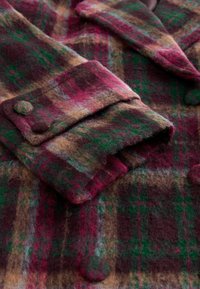 Villane ruuduline mantel, millel on burgundi, roheline ja pruun värvitoonide segu, tekstureeritud viimistlus, üle mõõde krae ja nööpidega mansetid.