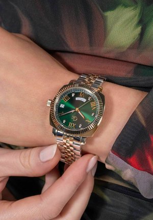 Orologio da polso in tonalità oro e argento con quadrante verde, numeri romani, finestra per la data e accenti di diamanti su un bracciale di metallo intrecciato.