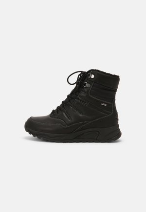 Bota de invierno aislante negra con cordones, suela resistente, cuello acolchado y ojales de metal, diseñada para clima frío y uso al aire libre.