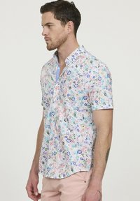 Korte mouwen, knoopsluiting shirt in het wit met een multikleuren bloemenpatroon. Beschikt over een lichtblauwe kraag en een zachte stoftextuur.