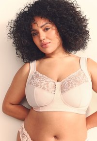 Beige trådløs bh med en blondepanel øverst, glat stof, brede stropper og en formet skål for komfort og støtte.