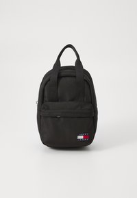 Mini sac à dos en nylon noir avec une poche avant zipp�ée et deux poignées supérieures. Présente une étiquette logo en rouge, blanc et bleu.