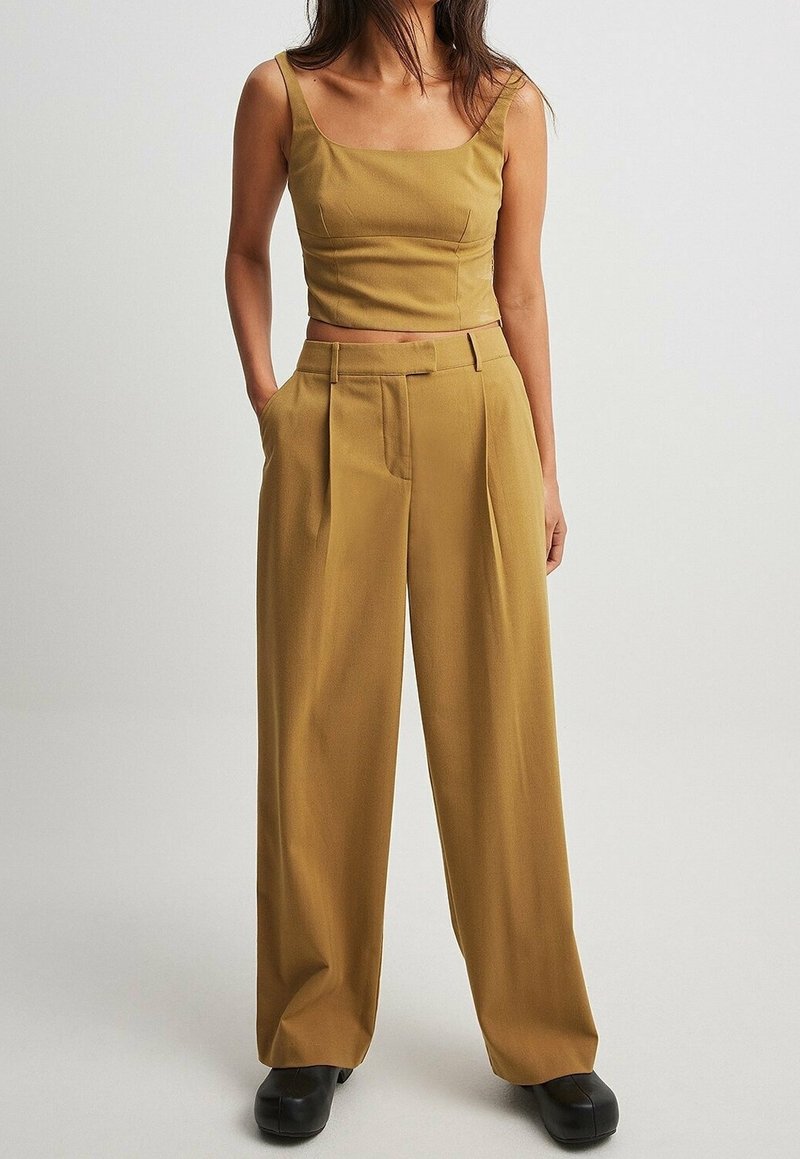 Musztardowa crop top z kwadratowym dekoltem i cienkimi ramiączkami, w połączeniu z szerokimi spodniami z przodowymi zaszewkami i kieszeniami bocznymi.