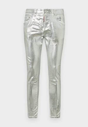 Metāliskās sudraba džinsi ar šauru piegriezumu, kam ir priekšējās kabatas, pogu aizdare un izteikts spīdums uz virsmas.