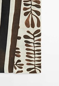 Textiel met abstracte bladpatronen in donkerbruin op een crèmekleurige achtergrond, met afwisselend zwarte en witte strepen langs de randen.