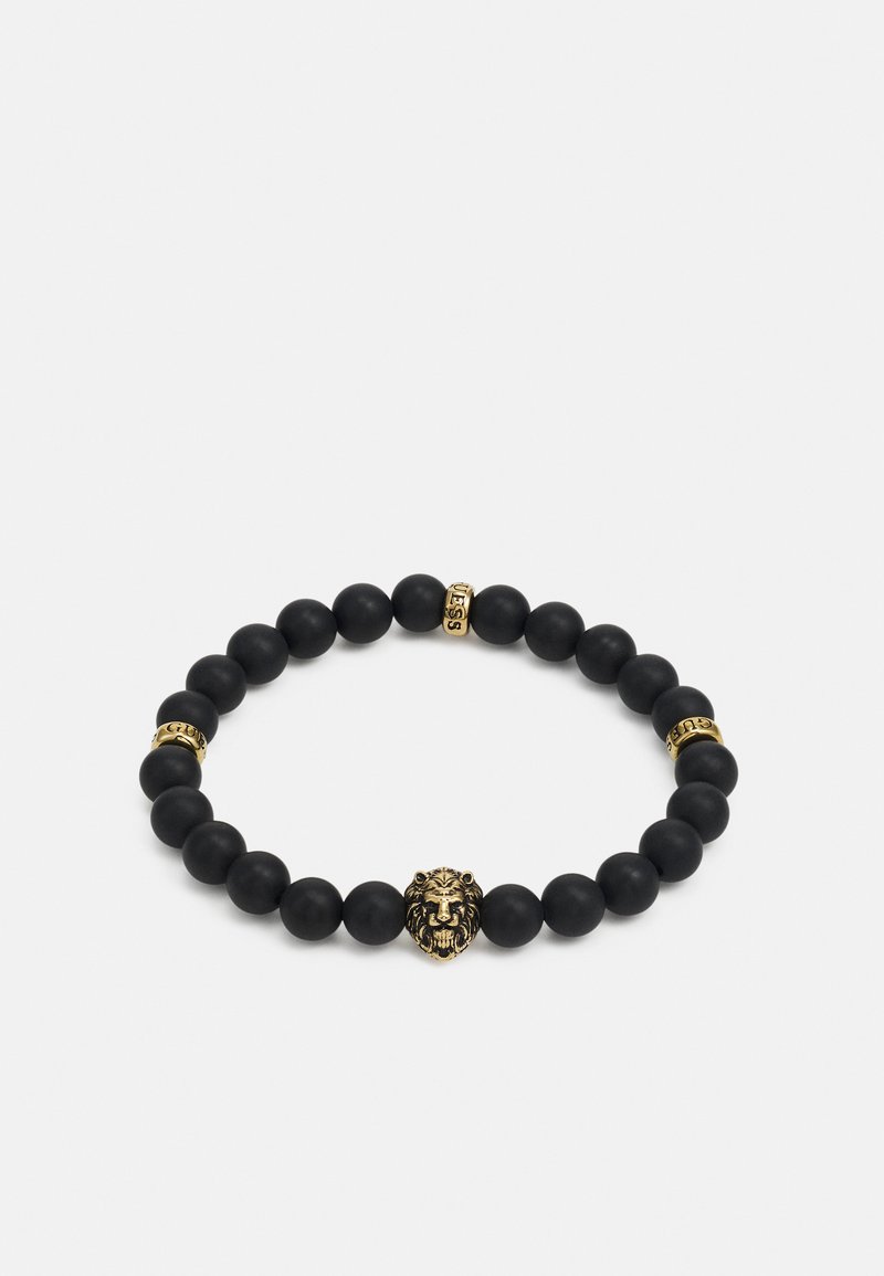 Pulseira preta com contas mate, um centro em forma de cabeça de leão dourada e dois destaques dourados com texto gravado. Design elástico para fácil uso.