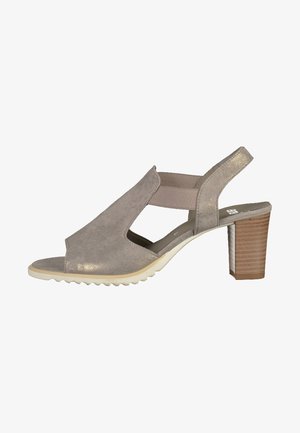 Sandale en daim beige à bout ouvert et design découpé, dotée d'une bande élastique beige et d'un talon en bois avec un détail texturé.