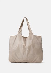 Beige stof tote bag med to skulderstropper, en glat glans og et subtilt præget logo i bunden, med et rummeligt, uspecificeret design.