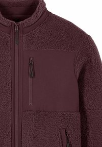 Veste en polaire d'un rouge bordeaux profond avec un corps texturé, des panneaux lisses sur la poitrine et les côtés, et trois poches zippées.