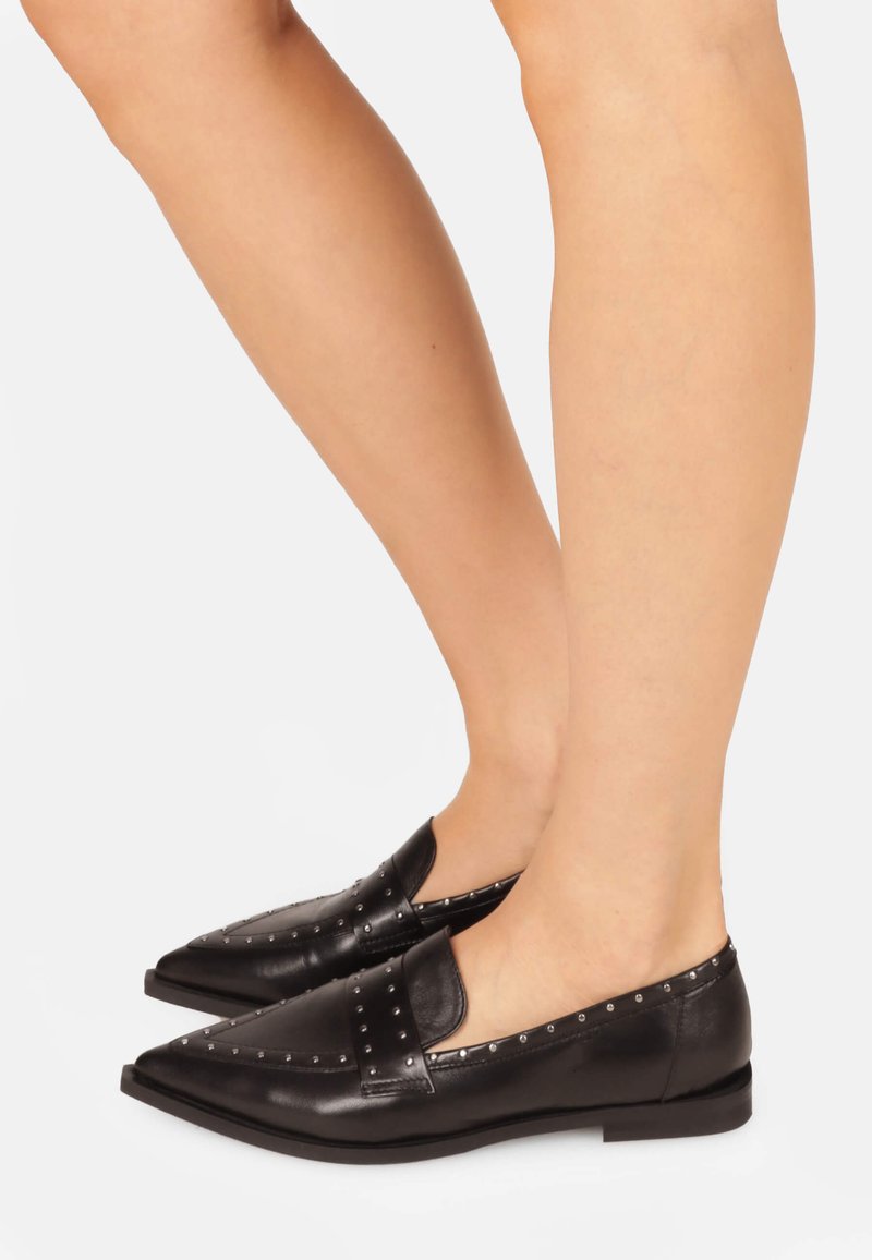 Black leather loafers with pointed toe, studded accents along the instep and heel, and a flat sole. Smooth texture and sleek design.